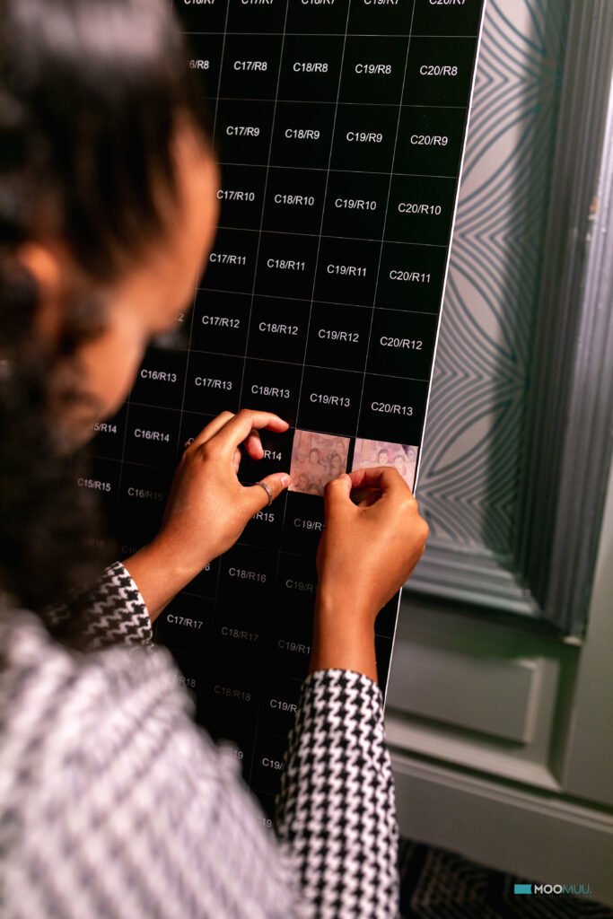 A person places a transparent card over a black grid filled with white alphanumeric codes on a board, with only their hands and part of their patterned sleeve visible—perfect for showcasing premium photo booth hire or corporate event experiential moments.