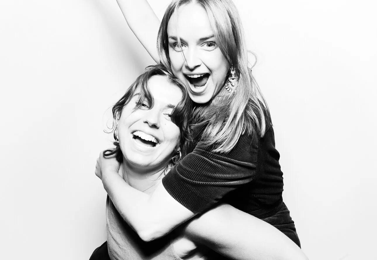 black and white photo of two female guests holding drinks and arm in the air