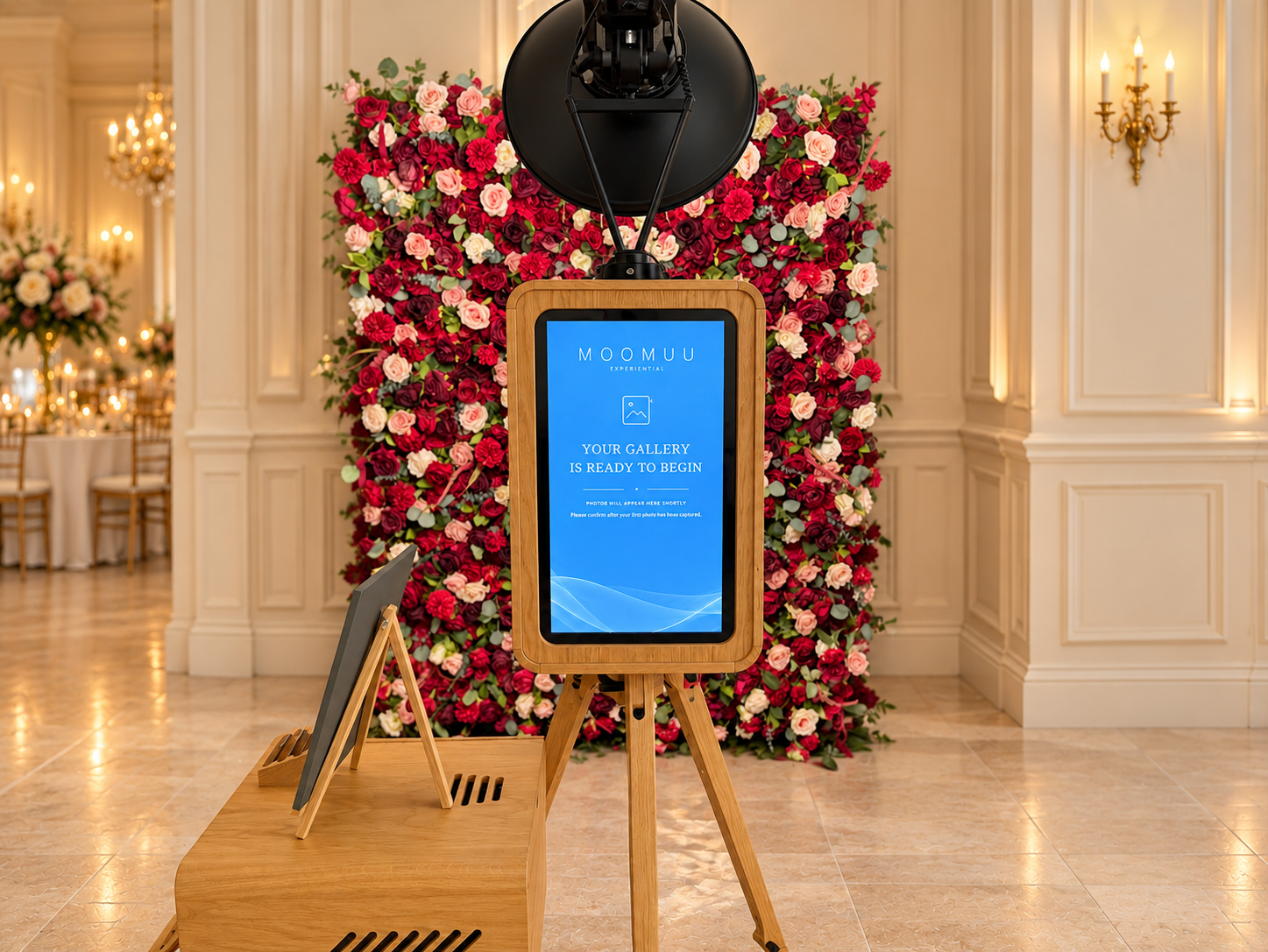 The ICON Booth rear touchscreen displaying a MooMuu gallery welcome screen in front of a red and pink flower wall.