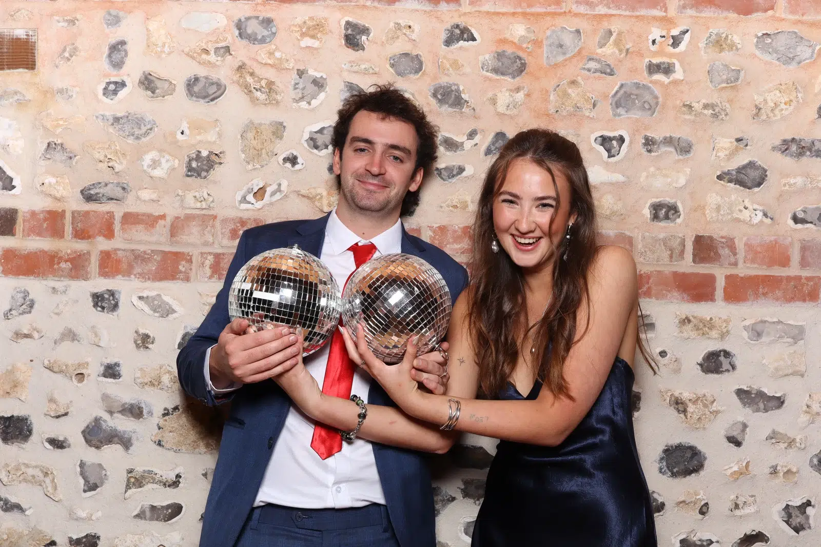 Two wedding guests laughing while holding small mirrored disco balls