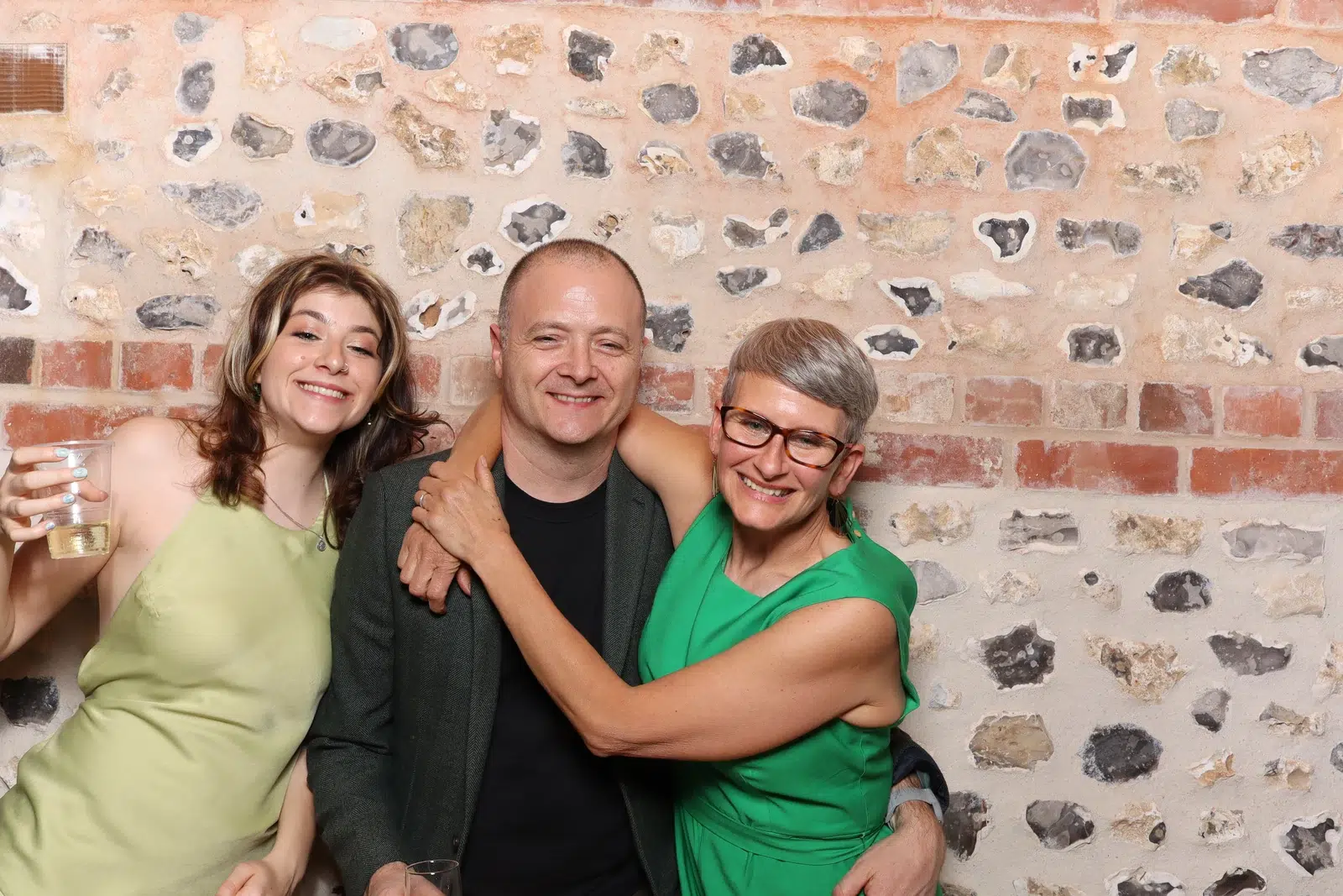 Three guests smiling together in a colourful group portrait at the wedding