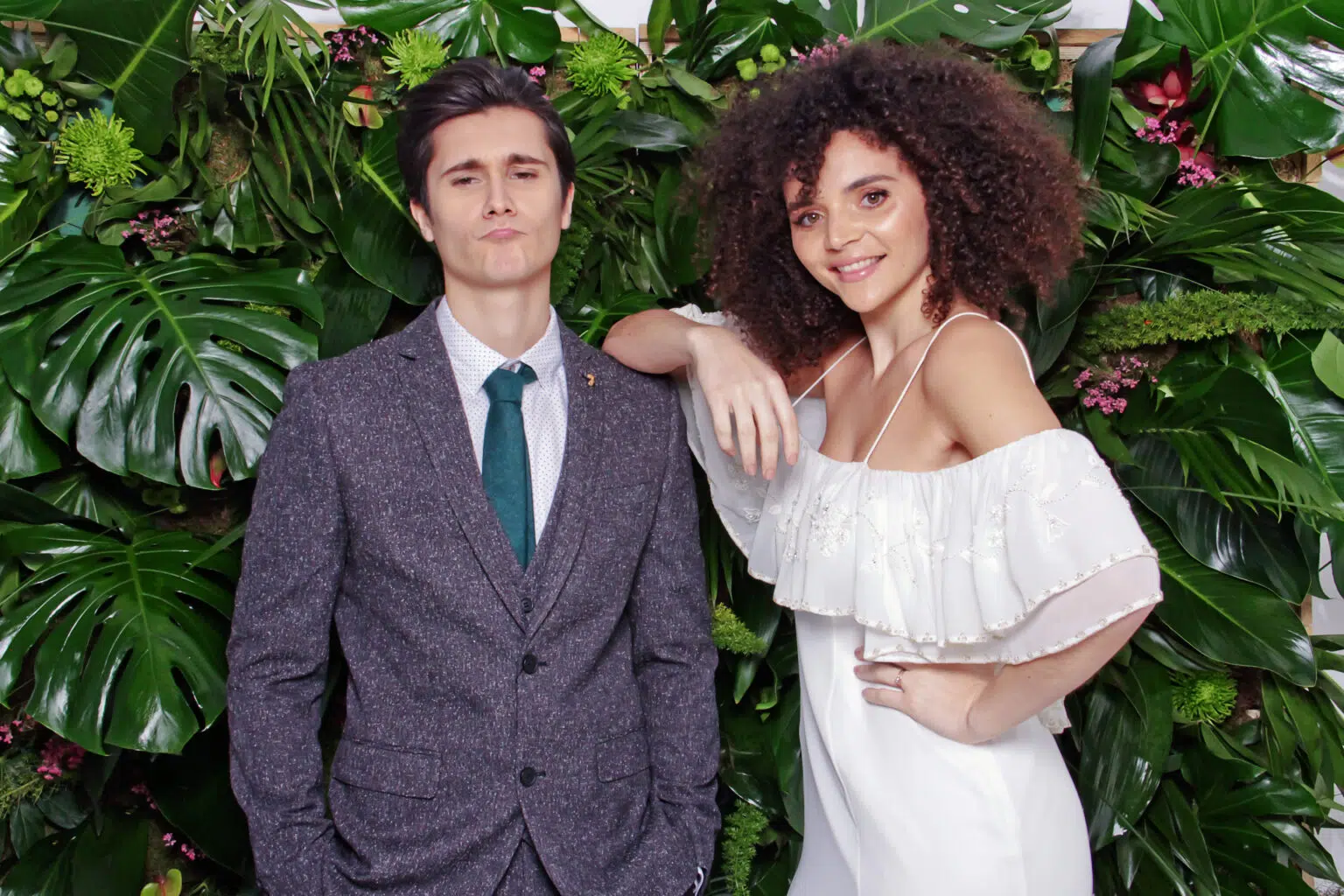 A couple posing for a colour portrait against a foliage backdrop.