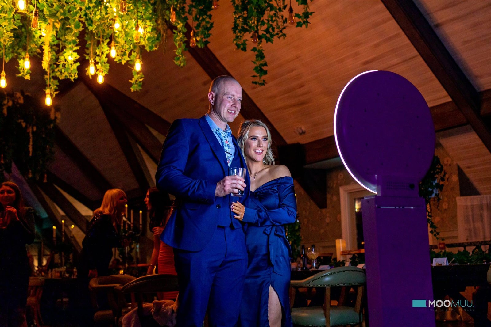 Couple enjoying the MooMuu Pearl photo booth at an evening celebration.