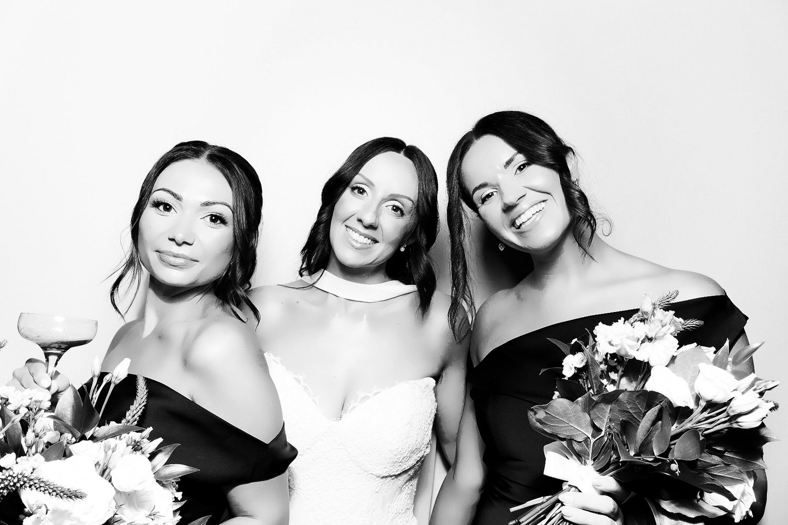 Bride and two guests holding bouquets in a black-and-white Signature GLAM group portrait.