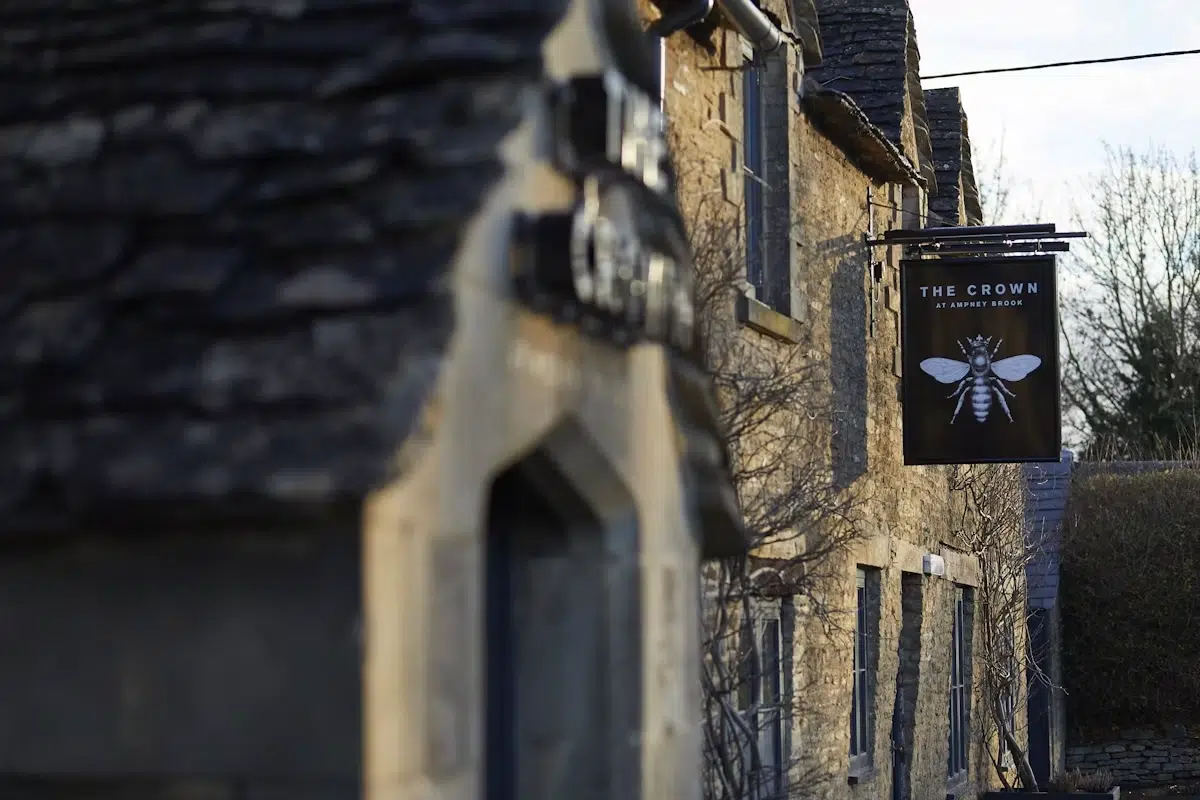 Cotswold stone exterior of Wild Thyme and Honey with The Crown at Ampney Brook sign