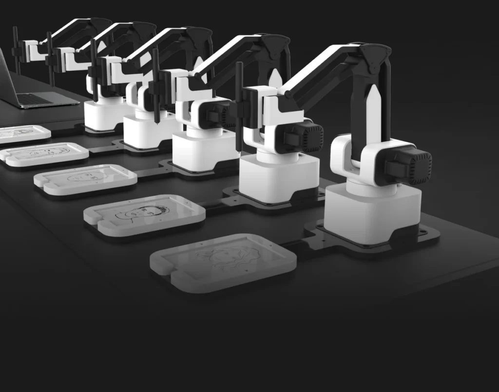 A row of robotic arms is lined up on a table, each near a rectangular tray with a transparent lid, set against a dark background—ideal for corporate event experiential setups. A laptop is partially visible on the left side.